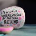 A rock with a written message that reads, "In a world where you can be anything BE KIND"